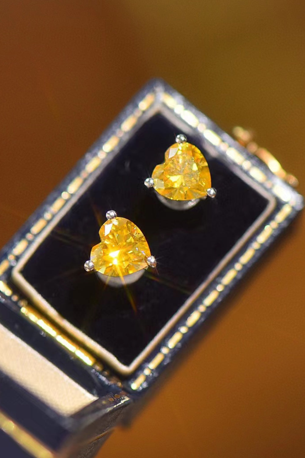 A pair of brilliant 1-carat each yellow heart-shaped moissanite earrings in a platinum-plated 925 sterling silver setting.